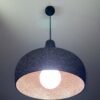 Black 3D printed pendant light glowing with warm copper interior, UMBRA design by 3Dcor